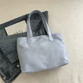 Light blue minimalist tote bag with wide straps on a grid background with books - Blue