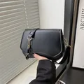 Minimalist black PU leather shoulder bag with gold hardware and unique wavy bottom edge - Black