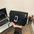 Elegant black square shoulder bag with silver trapezoidal metal buckle in a workplace setting - Black