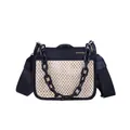 Woven straw crossbody bag with black leather trim and resin chain strap on white background - Black