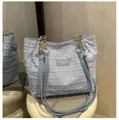 Dettaglio borsa tote azzurra in tweed con tracolla a catena dorata e marchio inciso - Blu