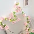 Guirnalda LED de flores de cerezo con hojas verdes envuelta en un cojín decorativo - Flor de Cerezo Rosa