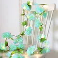 LED cherry blossom vine string lights with blue fabric flowers and green leaves on white chair - Blue Cherry Blossom
