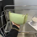 Hellgrüne Halbmond-Tasche aus genarbtem Leder mit goldener Kette in der Hand - Grün