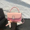 Pink patchwork crossbody handbag with silver buckle and top handle in a retail setting - Pink