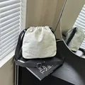Beige nylon drawstring bucket bag with adjustable black strap and fashion text detail - Off White