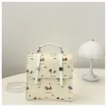 Detail eines Mini-Rucksacks mit Cartoon-Dackel-Prints und Kirsch-Bogen-Mustern - Beige