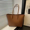Caramel large leather tote bag with litchi texture shown in a minimalist home setting - Brown