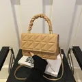 Quilted khaki crossbody bag with pleated handle and metal buckle on a black chair - Khaki
