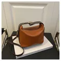 Bolso de mano marrón caramelo con rayas verticales, correas oscuras y hebilla dorada - Marrón