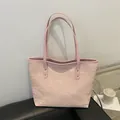 Pink tote bag with pleated texture and gold rivets leaning on a black sofa - Pink