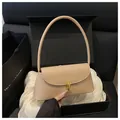 Bolso baguette beige con hebilla dorada presentado en elegante caja de regalo negra - Caqui
