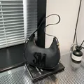 Minimalist black crescent shoulder bag featuring large 3D letters and gold hardware - Black