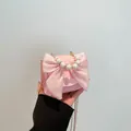 Pink crossbody bag with large satin bow and faux pearl handle shown in hand - Pink