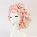 Detailed view of pink satin sleep bonnet with large bow on a mannequin head - Medium / Apricot