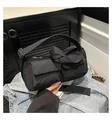 Close-up of black nylon crossbody bag with dual front pockets on denim jacket - Black