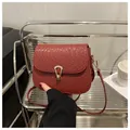Dettaglio della texture intrecciata e fibbia dorata a ferro di cavallo su borsa rossa - Rosso