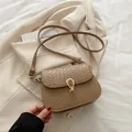 Khakifarbene Umhängetasche mit Webstruktur und goldenem Hufeisenverschluss auf beigem Blazer - Khaki