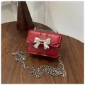 Mini red leather crossbody bag with silver bow accent and metal chain strap for girls - Red