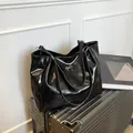 Grand sac cabas noir brillant avec nœud argenté posé sur une valise argentée - Noir