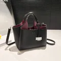 Elegante zwarte leren emmer tas met wijnrode binnenkant en zilveren metalen gesp - Zwart