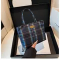 Detailaufnahme einer karierten Tragetasche mit Handmade-Plakette in einer Geschenkbox - Dunkelblau