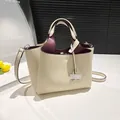 Elegante crèmekleurige lederen emmertas met bordeauxrode voering en verstelbare riem - Broken Wit