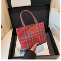 Detail der roten karierten Canvas-Tasche mit Messingplakette in einer edlen Geschenkbox - Rot