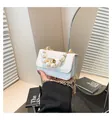 Detailed macro of white crocodile-textured mini bag featuring large pearl handle and gold lock - White