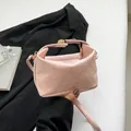 Borsa a secchiello rosa con trama intrecciata, dettagli dorati e tracolla su scrivania - Rosa
