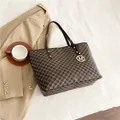 Classic dark brown tote bag with M letter print and gold pendant on white bedding - Brown
