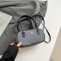 Gray textured pillow bag with black leather handles and golden logo detailing - Black