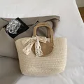 Schicke beige geflochtene Strohtasche mit braunen Rundgriffen und weißer Spitzenschleife - Mit Spitze Schleife / Khaki