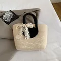 Beigefarbene gewebte Stroh-Tasche mit schwarzen Henkeln und weißer Spitzenschleife - Mit Spitze Schleife / Schwarz