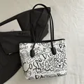 Weiße Canvas-Tragetasche mit schwarzen Graffiti-Prints auf grauem Blazer-Hintergrund - Weiß