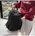 Vue détaillée du sac à dos minimaliste en toile noire avec plusieurs poches zippées - Noir