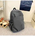 Vue détaillée du sac à dos gris en nylon avec poches latérales à cordon sur un bureau - Gris