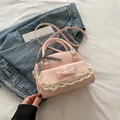 Pink PU leather crossbody bag with white lace trim and checkered bow on denim backdrop - Pink