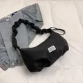 Borsa baguette nera in nylon con manico increspato sopra una giacca di jeans - Nero