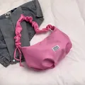 Pink pleated cloud baguette bag with scrunchie strap over a blue denim jacket - Pink