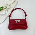 Chic red underarm bag featuring a silver metal bow buckle and woven leather texture - Red