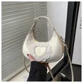 Close-up of cream hobo bag featuring delicate white heart-shaped lace and smooth satin finish - White