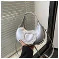 Detail view of silver moon bag with heart motif and lace trim against shutters - Silver