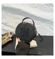 Black round crossbody bag with SM letter logo and lychee grain texture in hand - Black