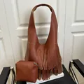 Brown litchi grain leather fringe tote bag set with matching zipper pouch on a chair - Brown