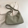 Green matte hobo tote bag with adjustable strap shown against a beige blazer jacket - No Pendant / Green