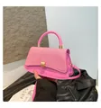 Detail view of pink crossbody bag with woven texture lid and golden metal lock - Pink