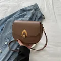 Sacoche marron chic avec boucle en arche dorée et bandoulière fine sur denim bleu - Marron