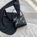 Borsa tote in pelle nera minimalista con fiocchi bianchi su sfondo in tessuto testurizzato - Nero