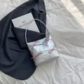 Borsa a spalla argento metallizzato con fiocchi rosa e manico sottile su sfondo abito blu - Argento